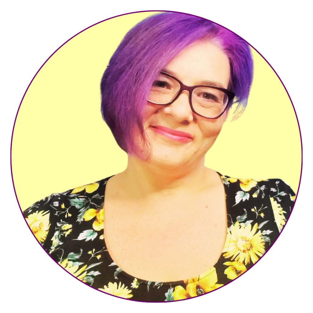 A woman with purple hair and glasses, wearing a black top with sunflowers on it.